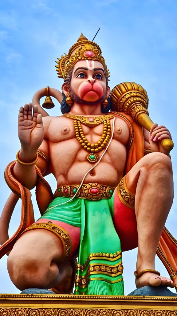 Majestic statue of Lord Hanuman with a golden gada (mace) and a blessing hand, symbolizing strength, devotion, and protection in an HD phone wallpaper
