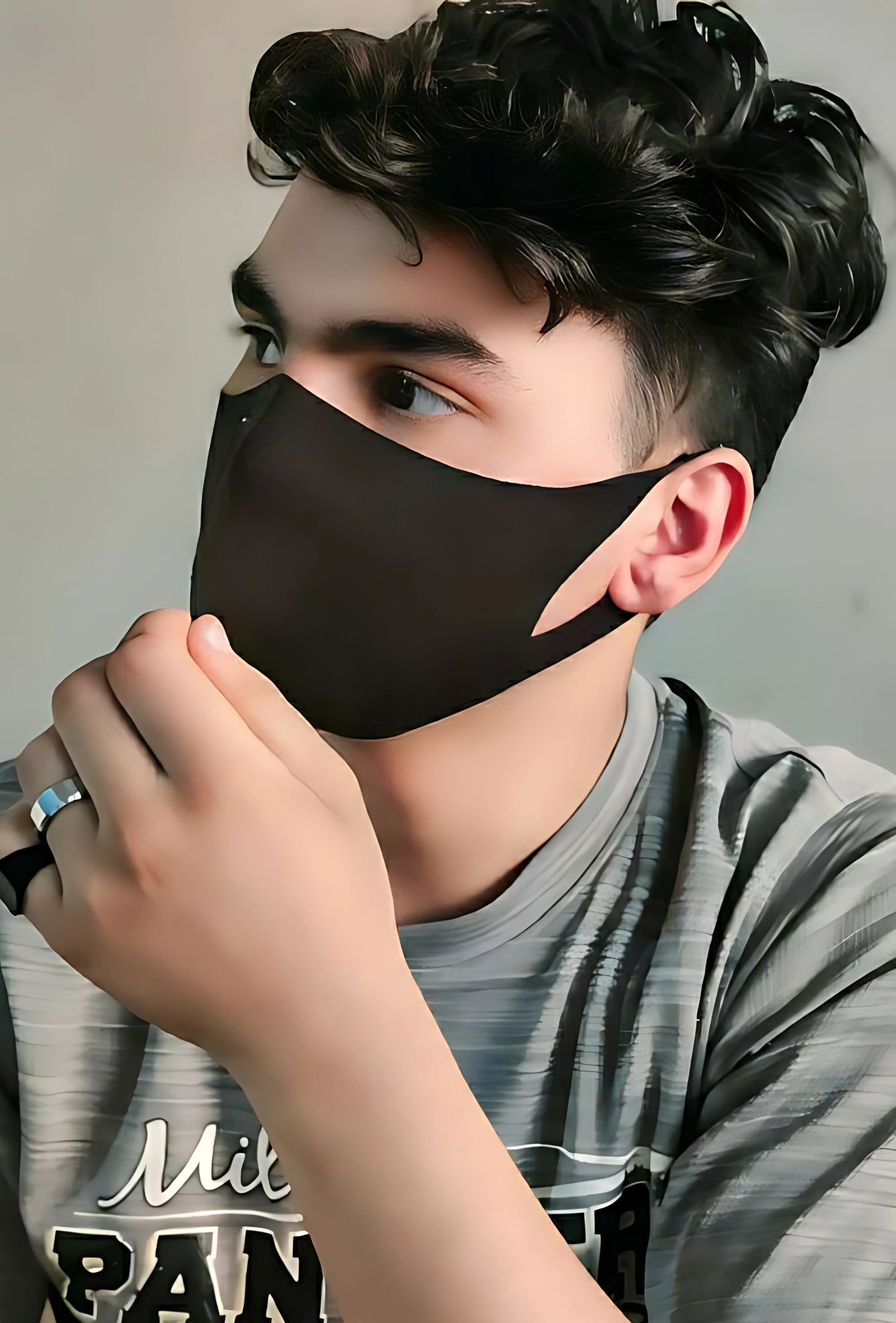 Handsome boy wearing a black mask, looking sideways, dressed in a striped gray T-shirt