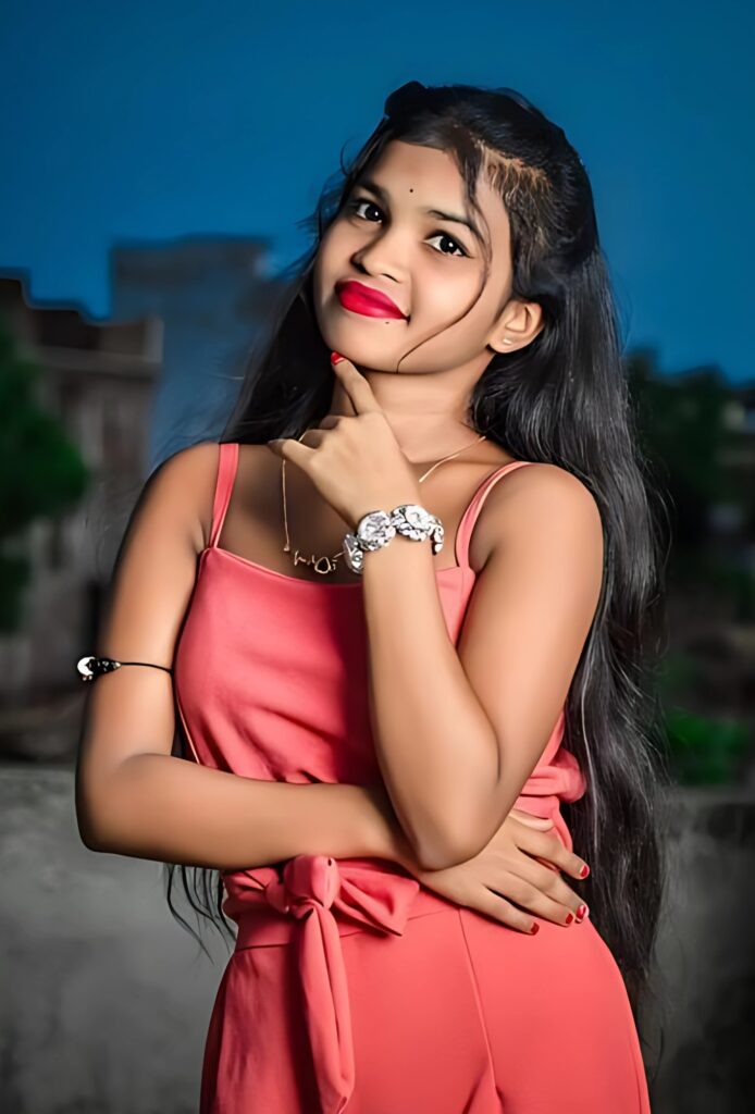Stylish Indian girl in a sleeveless pink dress posing confidently outdoors with a vibrant background
