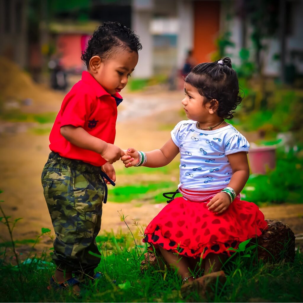 Cute baby couple holding hands outdoors in a natural setting, sharing an innocent and heartwarming moment – perfect WhatsApp DP for baby lovers