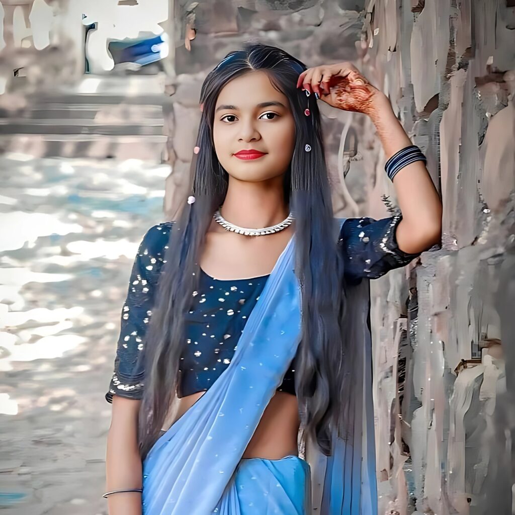 Cute Indian girl in blue saree posing with smile against stone wall background
