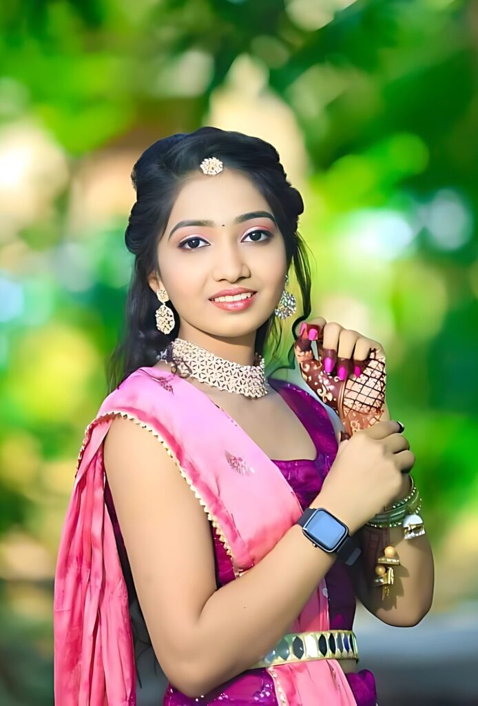 Beautiful Indian girl in pink traditional attire with jewelry and mehndi design, smiling outdoors in natural light.