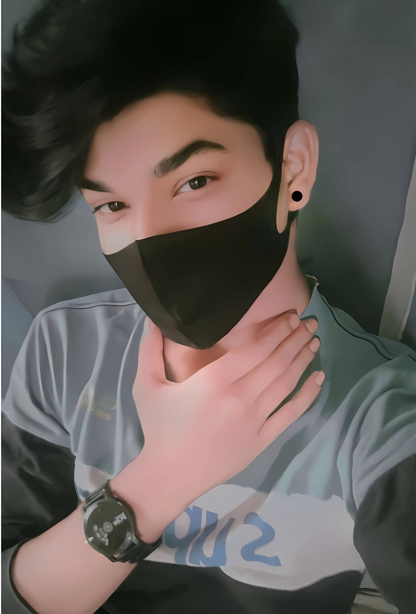 Stylish boy wearing a black mask with dark hair, watch, and hand on neck posing indoors