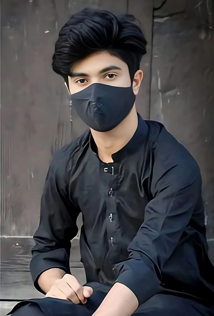 Boy in black traditional outfit and face mask, seated confidently with a modern smartwatch