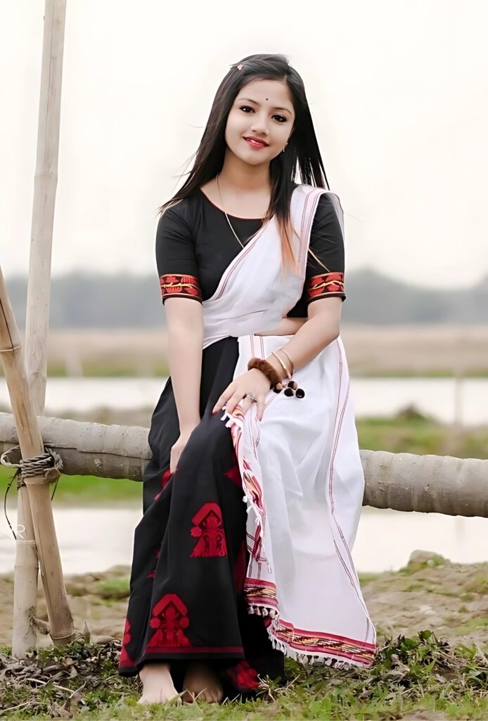 Beautiful Indian girl in traditional Assamese attire posing outdoors with a natural village background.