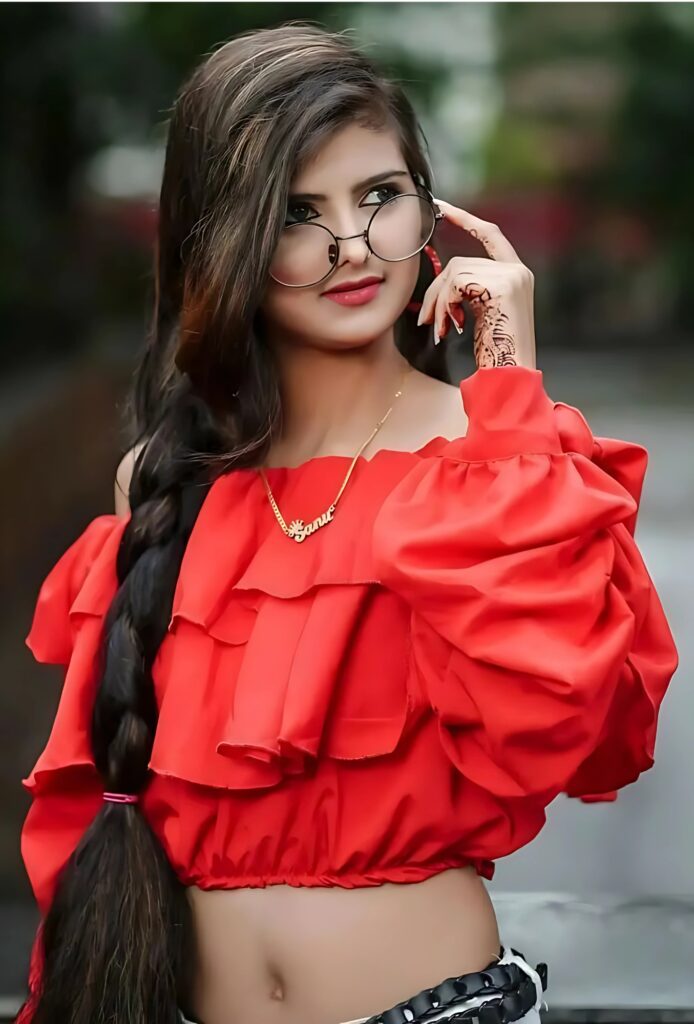 Stylish Indian girl wearing red ruffle top with long braided hair, round glasses, and mehndi design, outdoor fashion photoshoot