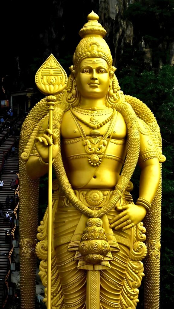 Towering golden statue of Lord Murugan holding a Vel at Batu Caves, Malaysia, representing the Hindu god Kartikeya in HD