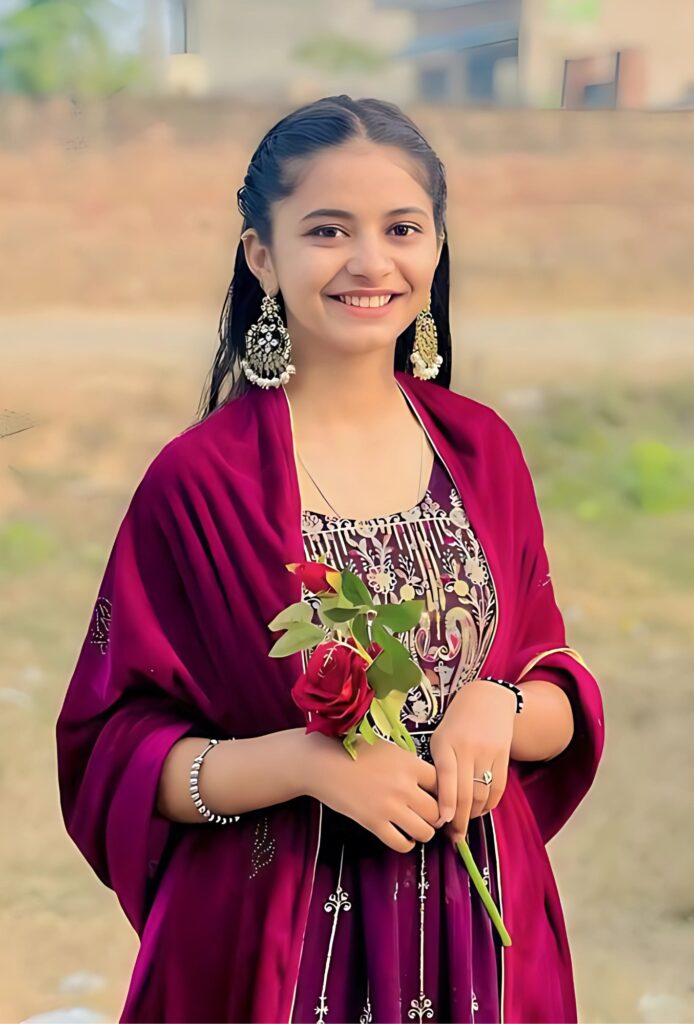 गुलाबी ट्रेडिशनल ड्रेस में हाथ में गुलाब का फूल पकड़े हुए मुस्कुराती हुई सुंदर भारतीय लड़की।
