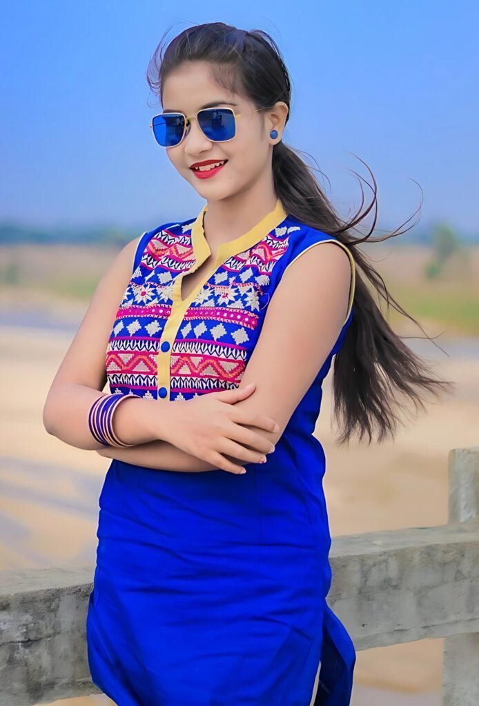 ब्लू सूट और स्टाइलिश सनग्लासेस में खुले बालों वाली भारतीय लड़की, खुले आसमान के नीचे।