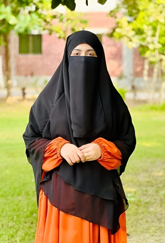 हिजाब पहनने वाली लड़की नारंगी ड्रेस और काले नकाब में बगीचे में खड़ी – नई इस्लामिक प्रोफाइल फोटो HD