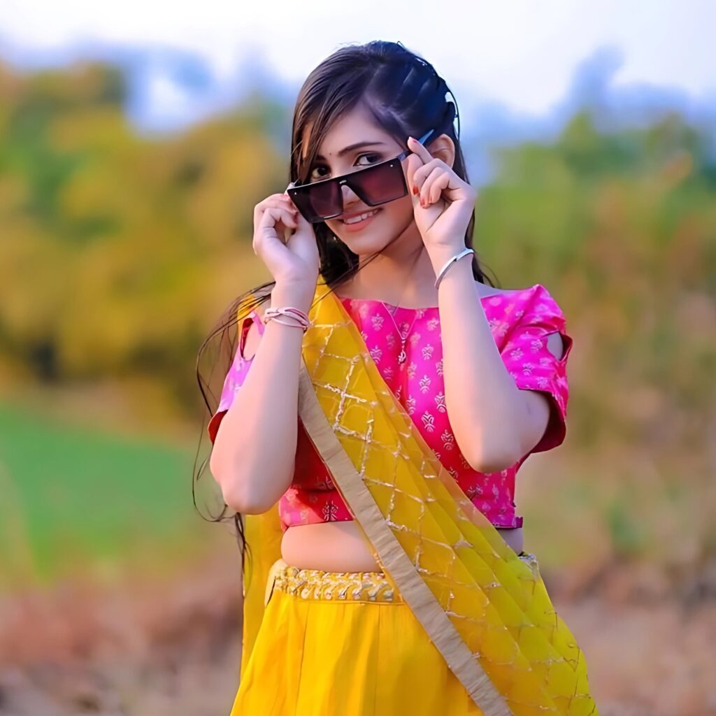 Cute Indian girl in colorful traditional attire with sunglasses – charming WhatsApp DP pose in nature.