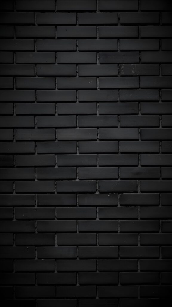 Aesthetic black brick wall texture wallpaper with a matte finish and subtle lighting for a dark, minimalist background.
