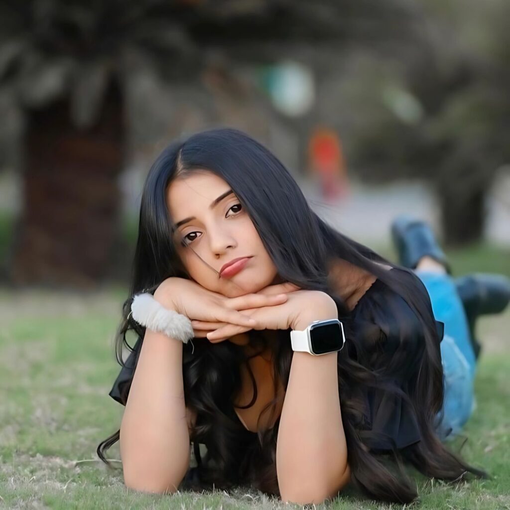 Stylish girl lying on grass with a pouting expression, wearing black outfit, long wavy hair, and a smartwatch – perfect for trendy WhatsApp DP for girls.