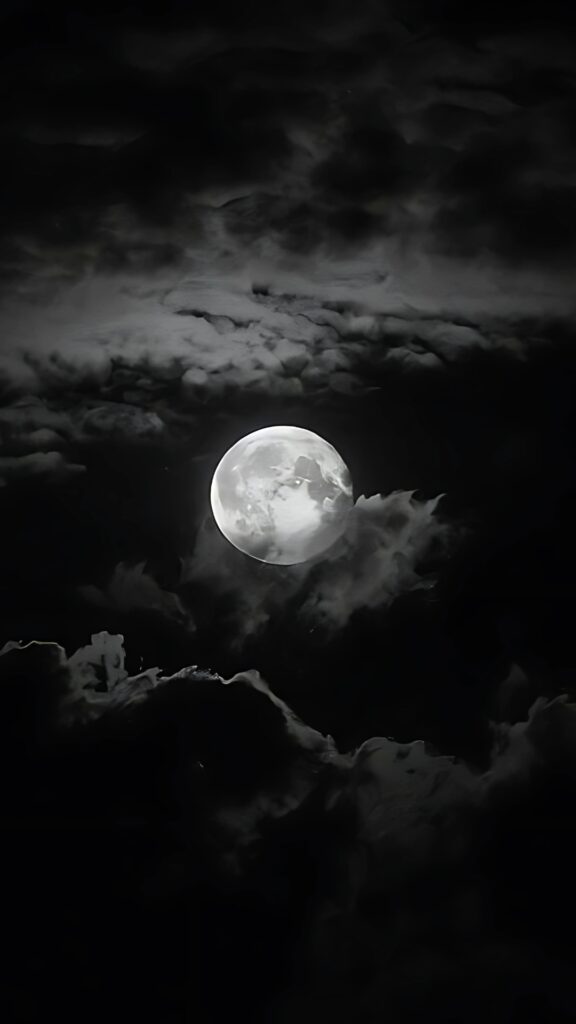 Dark aesthetic wallpaper featuring a glowing full moon surrounded by dramatic clouds in a moody night sky
