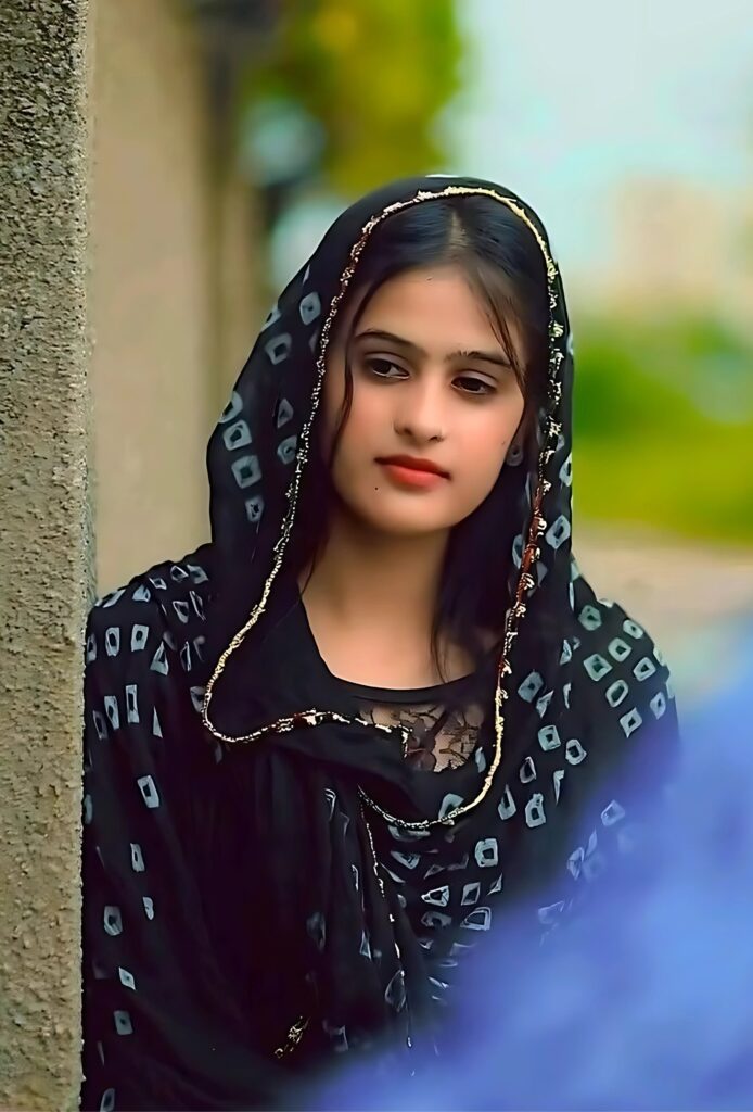 Muslim girl wearing a black dupatta with traditional print, looking to the side in a natural setting
