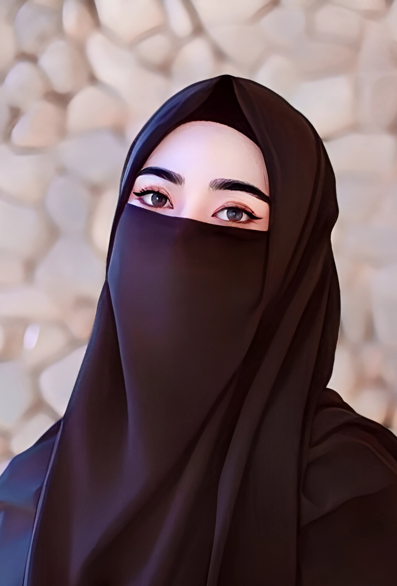 Beautiful hijab girl wearing black niqab with expressive eyes and stone wall background – HD Islamic profile picture.