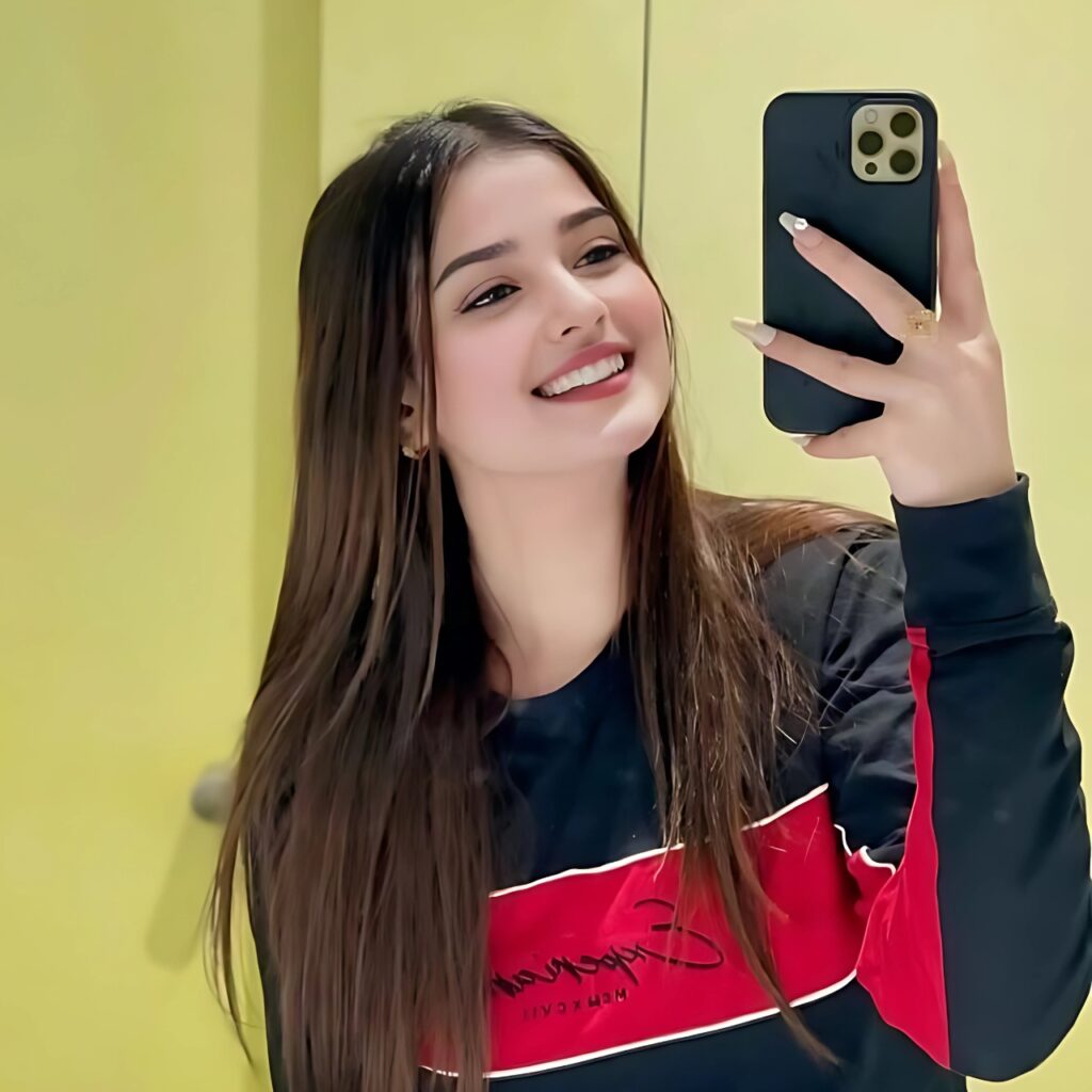 Modern girl taking a mirror selfie with a smile, wearing a black and red outfit – trendy WhatsApp DP for girls.
