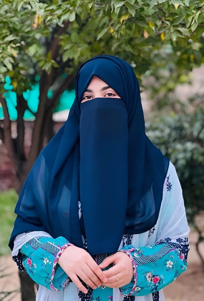 New hijab girl DP in navy blue niqab and floral dress standing outdoors with greenery background – HD Islamic profile picture.