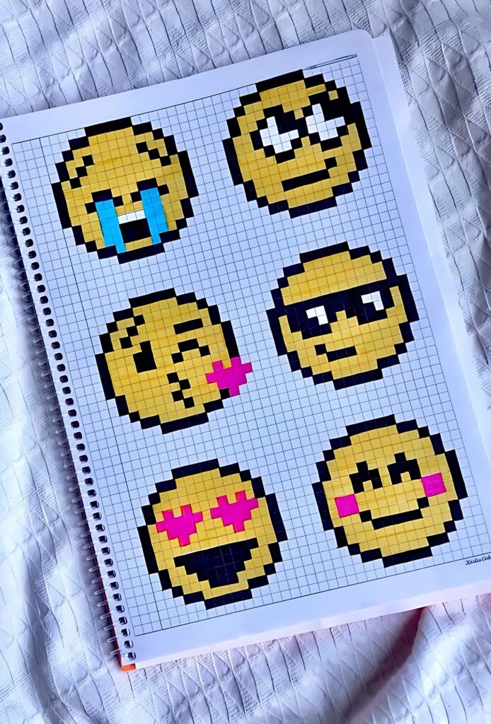 Cuaderno con dibujos pixelados de emojis pequeños y coloridos, incluyendo caritas llorando, enamoradas, con gafas y guiños, hechos sobre papel cuadriculado.